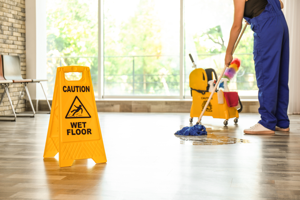 Person Cleaning Floor with Wet Floor Sign